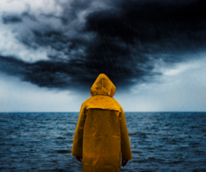 Man stands in front of ocean and watches storm, symbolizing understanding anger management