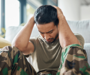 image of distraught male soldier dressed in battle fatigues clutching his head as a metaphor for understanding severe PTSD in veterans